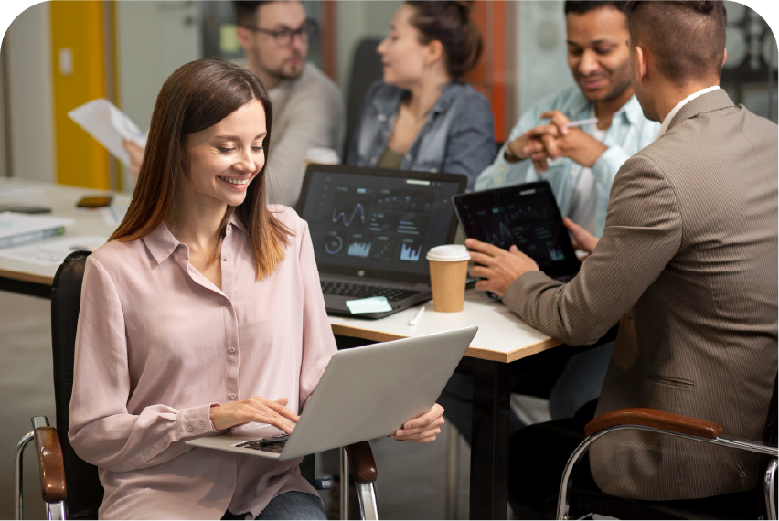 A diverse team collaborating on a project using laptops and tablets in a bright, modern office.