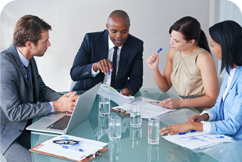 A diverse team collaborating on a project using laptops, paperwork and tablets in a bright, modern office.